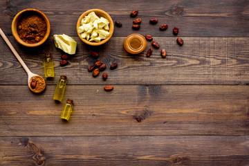 Pieces of cocoa butter and cacao powder in bowl for homemade cosmetics. Dark wooden background top view copy space