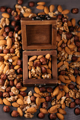 Wooden box full of nuts. Mix of hazelnuts, walnuts and almonds on the table, vertical frame