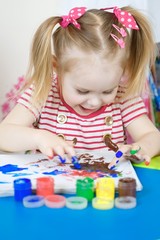 Cute girl shows dissapointment and sad emotions due to covered with paint hands and fingers