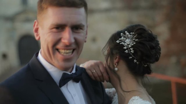 A young and beautiful wedding couple standing together on the bride near the old castle and smile. Wedding day. Slow motion