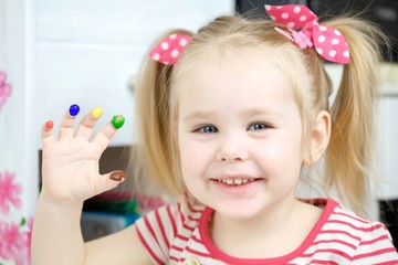 Cute girl shows dissapointment and sad emotions due to covered with paint hands and fingers