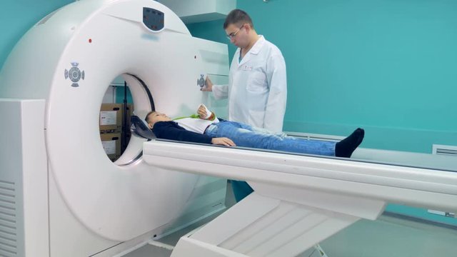 Male doctor preparing a boy for an MRT scanning procedure