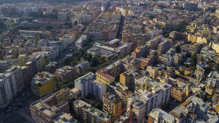 Obraz premium Aerial view of a group of buildings in the Tuscolana district in Rome, city e capital of Italy. The roofs are passable and with antennas and TV. down the sun lit streets there are cars and trees.