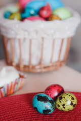 Easter. Colored eggs of chicken and quail, cake lay in wicker basket.