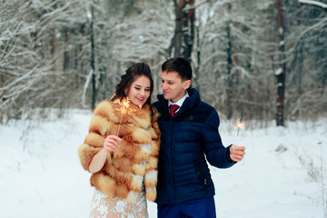 Beautiful bride in a fur coat in a winter pine forest with a wedding bouquet
