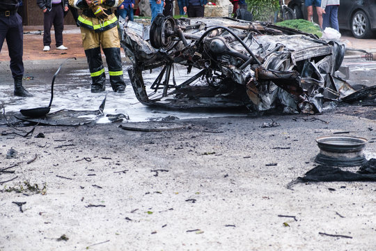 Burned car after an accident on the road. Firefighter standing nearby. Reportage picture of accident