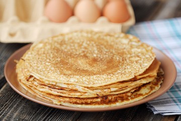 Fresh pancakes and eggs on a wooden table