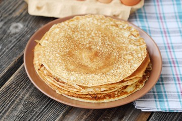 Fresh pancakes and eggs on a wooden table