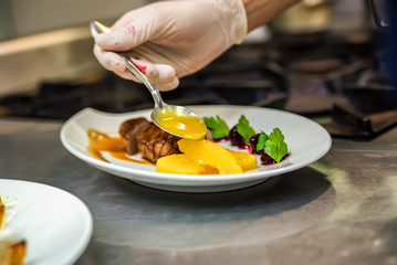 Hand adds sauce to steak
