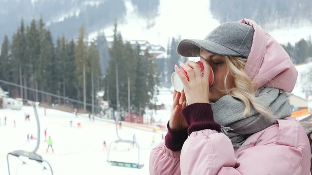 portrait smiling stylish attractive young woman drinking hot coffee outside top mountains stunning winter landscape background people skiing ski lift active sport lifestyle wanderlust traveling