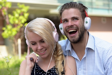 Man with woman enjoy music outdoor with urban background, defocused