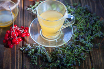 Herbal vitamin herbal tea with thyme in a transparent glass mug on a wooden table
