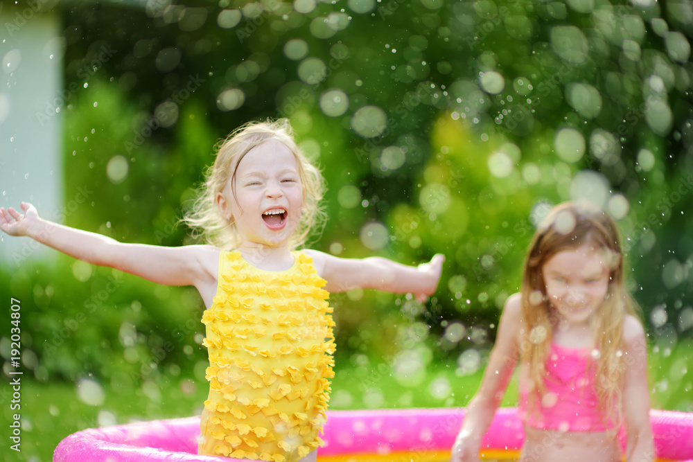 Canvas Prints Adorable little girls playing in inflatable baby pool. Happy kids splashing in colorful garden play center on hot summer day.