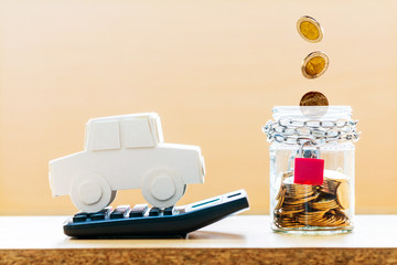 Car model put on the calculator and coin drop in the jar bank with security with growing in the office, loan and saving for buy a new car and business investment property concept.