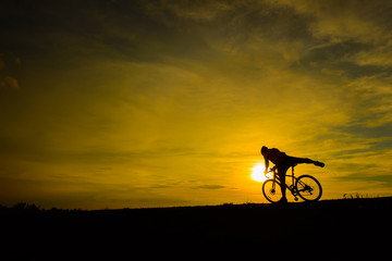 Obraz premium Silhouette of handsome man with bicycle on sunset,sport man concept