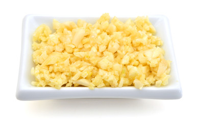 Sliced garlic in white bowl on white background