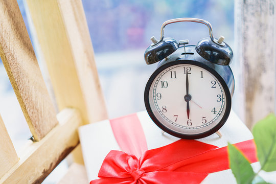 Alarm clock on the gift boxe christmas with red ribbin.