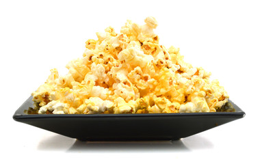 fresh popped popcorn isolated in black plate on white background