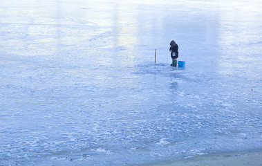 Fototapeta na wymiar A winter fisherman on ice is fishing.