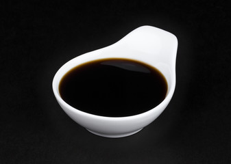 Soy sauce in white bowl on black background