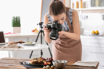 Young woman with professional camera taking still life pictures in kitchen