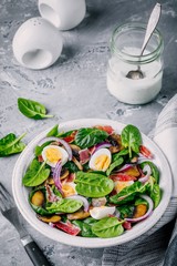 lunch bowl of spinach salad with bacon, mushrooms, eggs and red onions