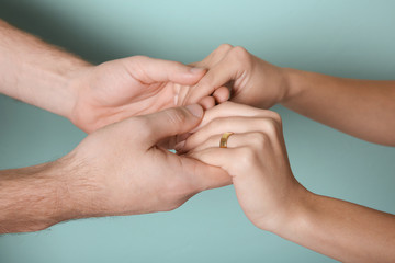 Young couple holding hands together on color background