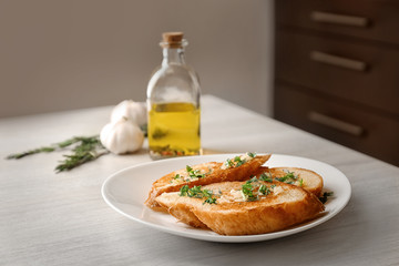Plate with delicious homemade garlic bread on table