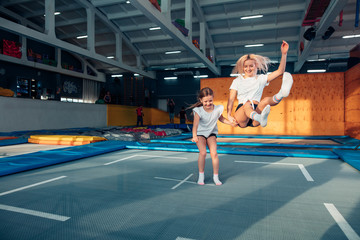 mother and daughter jumping on trampoline and doing split indoor