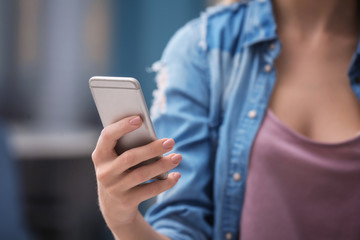 Woman with cell phone indoors, closeup