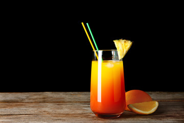 Glass of Sex on the Beach cocktail on wooden table against dark background