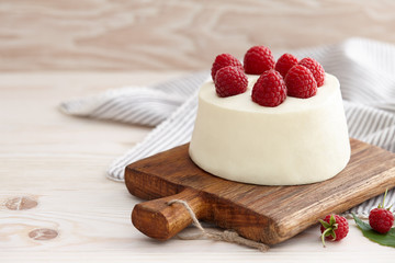Raspberry mousse cake with fresh raspberries on wooden board