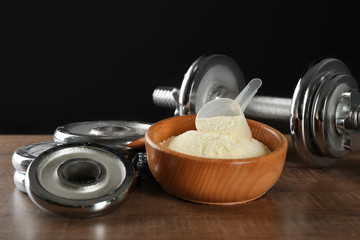 Bowl with protein powder and dumbbell on table