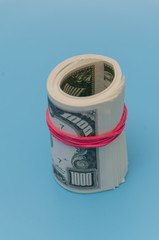 on a blue background pack of a thousand dollars tied with a rubber band