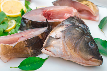 Raw fish with greens on a white cutting board