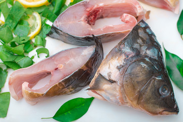 Raw fish with greens on a white cutting board