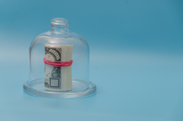 place under the inscription, a pack of dollars under the glass cap, on a blue background