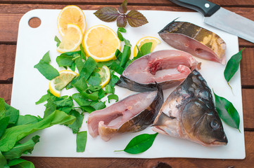 Raw fish with greens on a white cutting board