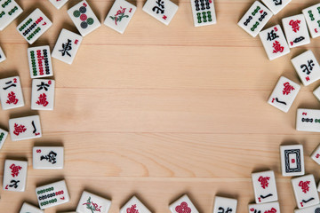 White-green tiles for mahjong on a background of light brown wood. Empty space in the center - obrazy, fototapety, plakaty