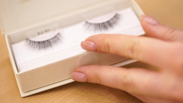 Eyelash extensions and eyebrows. False eyelashes in female hands. The girl takes out false eyelashes from the package