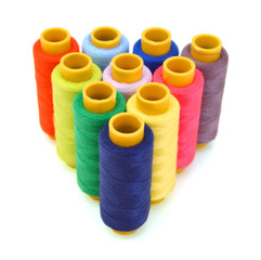 Pyramid of many-coloured bobbins of thread isolated on white