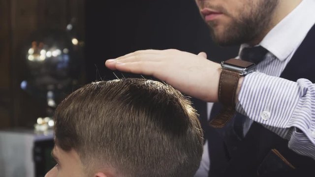 Cropped clsoe up of a professional barber spraying water on the hair of his client while styling it profession job career occupation entrepreneurship lifestyle traditional barbering barbershop.
