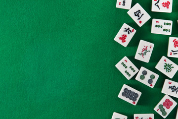 White-green tiles for mahjong on on green cloth background. Emty space on the left