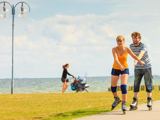 Fototapeta premium Young couple on roller skates riding outdoors