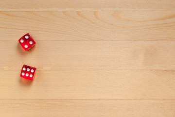 Red dice on a light brown wooden background