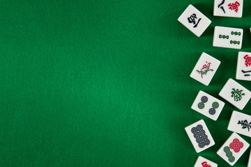 White-green tiles for mahjong on on green cloth background. Emty space on the left - obrazy, fototapety, plakaty