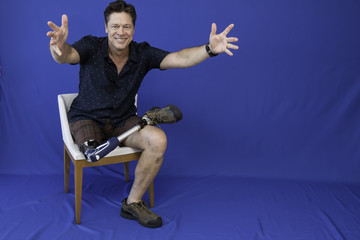 Obraz premium Middle-aged man with physical disability, happy with life sitting on the chair