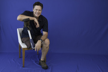 Middle-aged man with physical disability, happy with life sitting on the chair