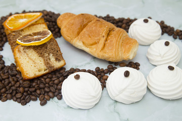 Dried orange, croissant, marshmallows, toasters and coffee beans on white stone background