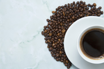 Coffee cup and coffee beans on white stone background. Top view